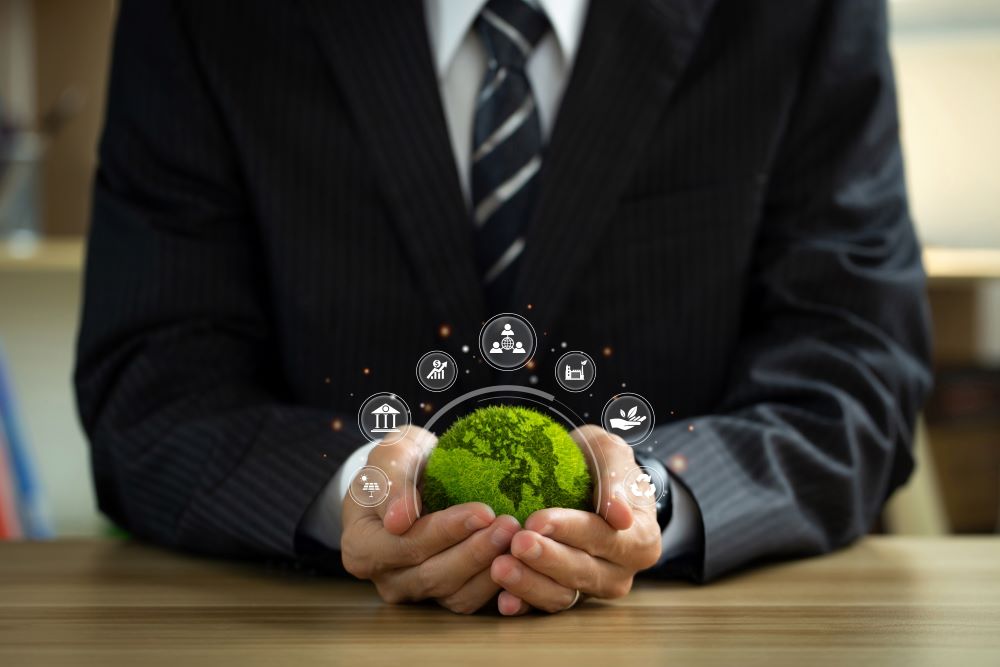 Person in a suit holding a small green globe surrounded by icons representing sustainability and technology.