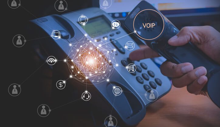 A hand holding a VoIP phone with digital icons and network connections superimposed, depicting modern communication technology.