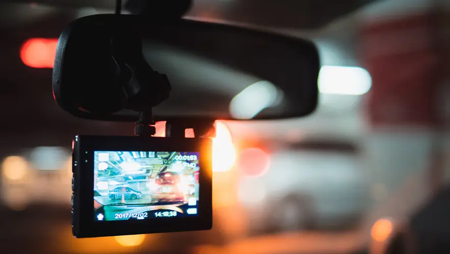 Dashcam recording through a car's windshield, seamlessly capturing traffic with blurred lights in the background, much like sophisticated security camera systems do.