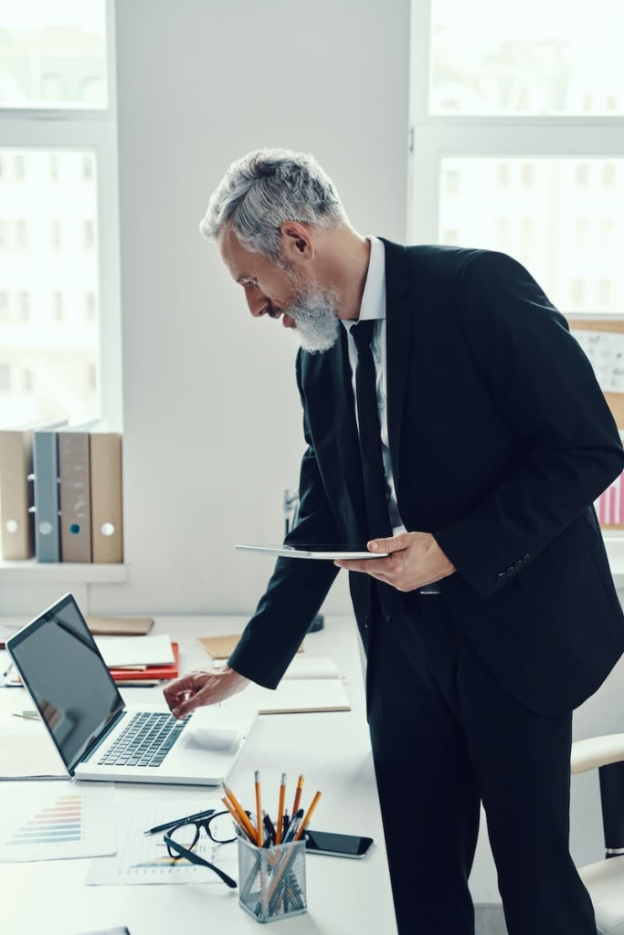 Man in a suit using a laptop at an office desk.