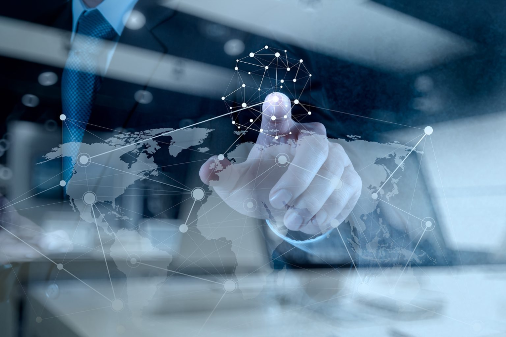 A businessman in a suit touches a virtual screen displaying a world map and digital network connections, symbolizing global business and technology.